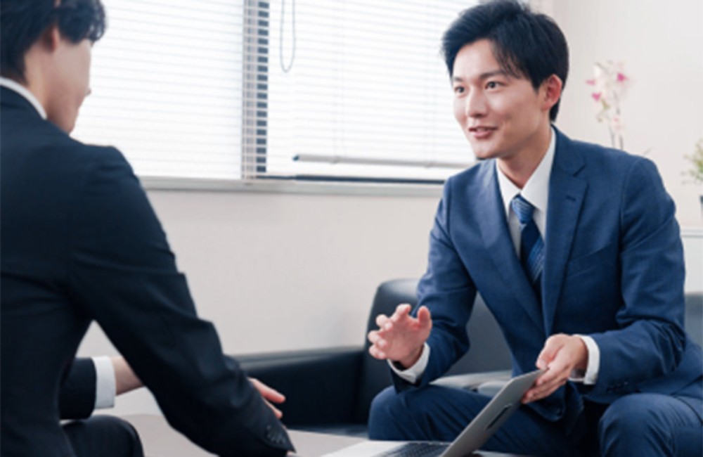 議事録ツールの利用シーンを示す画像。ビジネスマンが会議室で話し合っている様子。