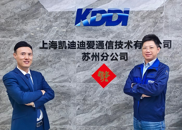 Two smiling KDDI representatives stand in front of KDDI Shanghai