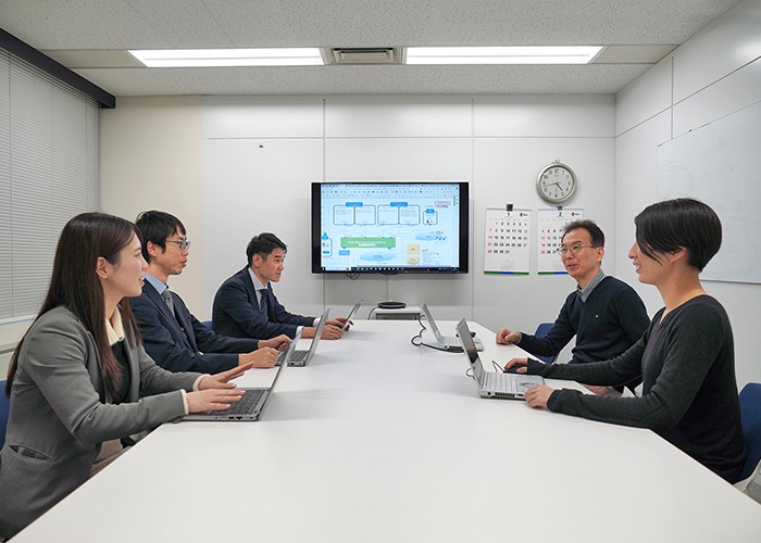 KDDI担当者と佐藤様、岡本様が向かい合って打ち合わせをしている
