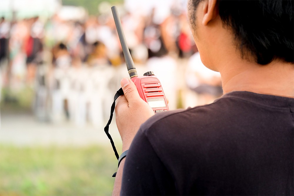 イベント会場においてトランシーバーで会話する男性スタッフ