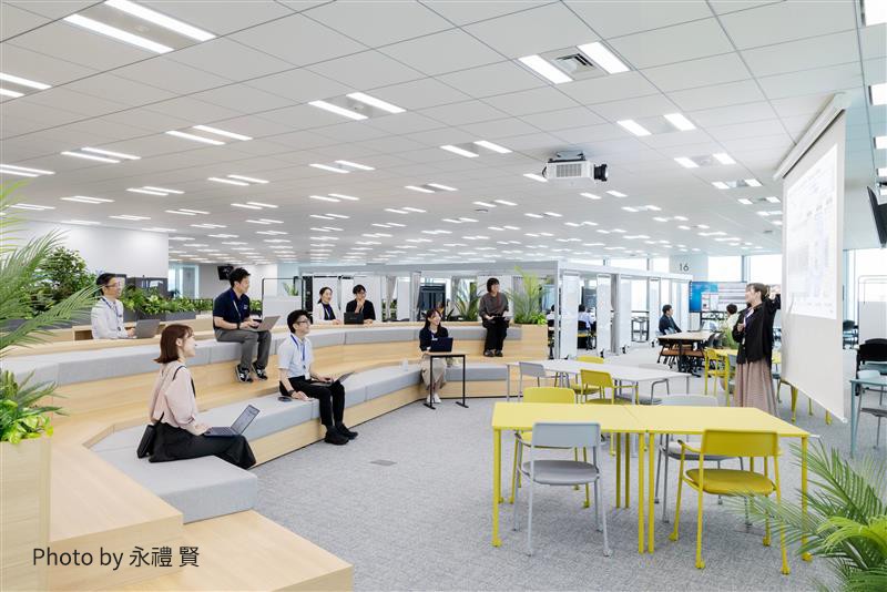 広い会議室やセミナールームで、数人の人が座っている様子。スクリーンやプロジェクターを使ったプレゼンテーションの場面。（Photo by 永禮 賢）