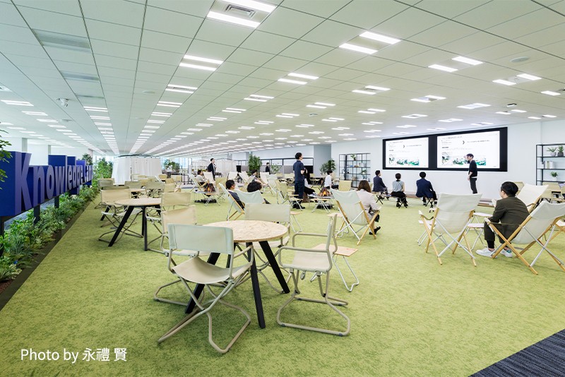 広々とした会議室やプレゼンテーションスペースで、複数の人が座っている様子。大きなスクリーンと照明が設置されている。（Photo by 永禮 賢）