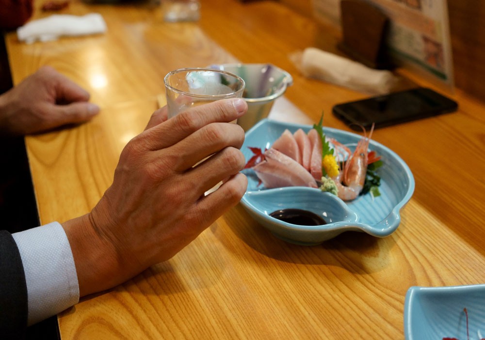 酔って居酒屋のテーブルの奥にスマホを置き忘れるビジネスマン